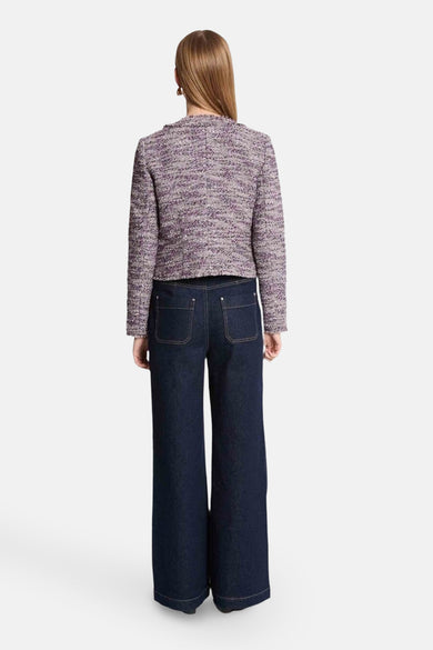 Veste courte mauve de Morgan de Toi, avec une texture tweed et portée avec un jean bleu large.