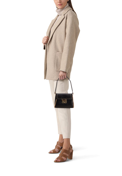Sac à bandoulière noir de Morgan de Toi avec quincaillerie dorée et porté avec un manteau beige.