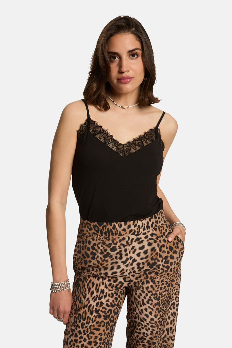 Zwarte kanten hemdje met spaghettibandjes van Morgan de Toi, gedragen met een broek met luipaardprint en zilveren armbanden.
