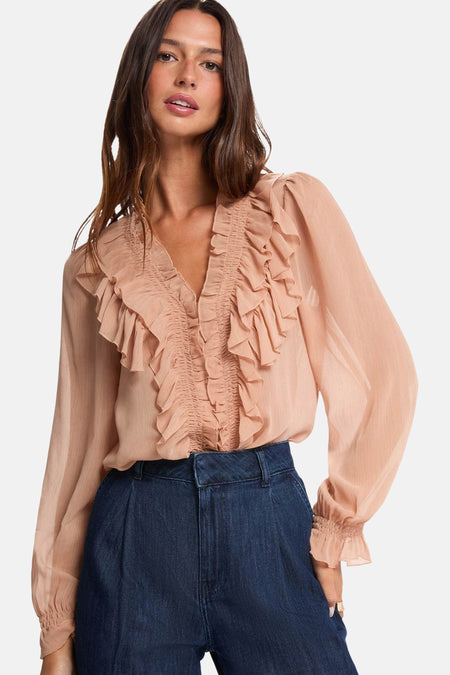 Blouse à manches longues beige van Morgan de Toi, avec des volants décoratifs sur le devant et portée avec un pantalon taille haute.
