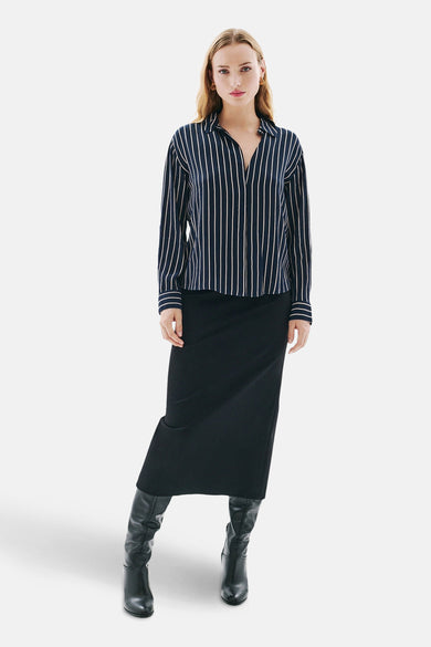 Blauw gestreept overhemd met lange mouwen van CAROLL, gedragen met een zwarte rok en leren laarzen.