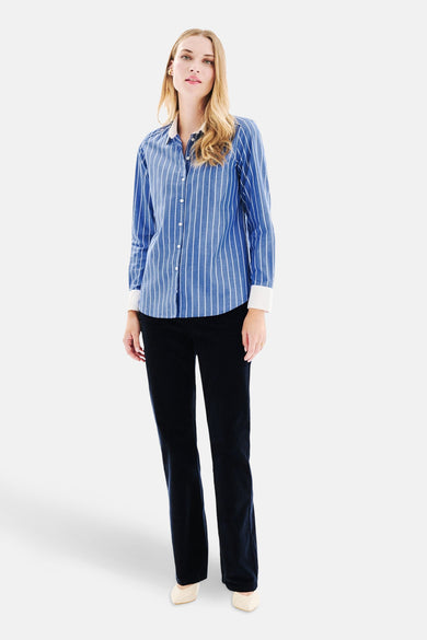 Blauwe blouse met lange mouwen en witte strepen van CAROLL, gedragen met een donkere broek en crèmekleurige schoenen.