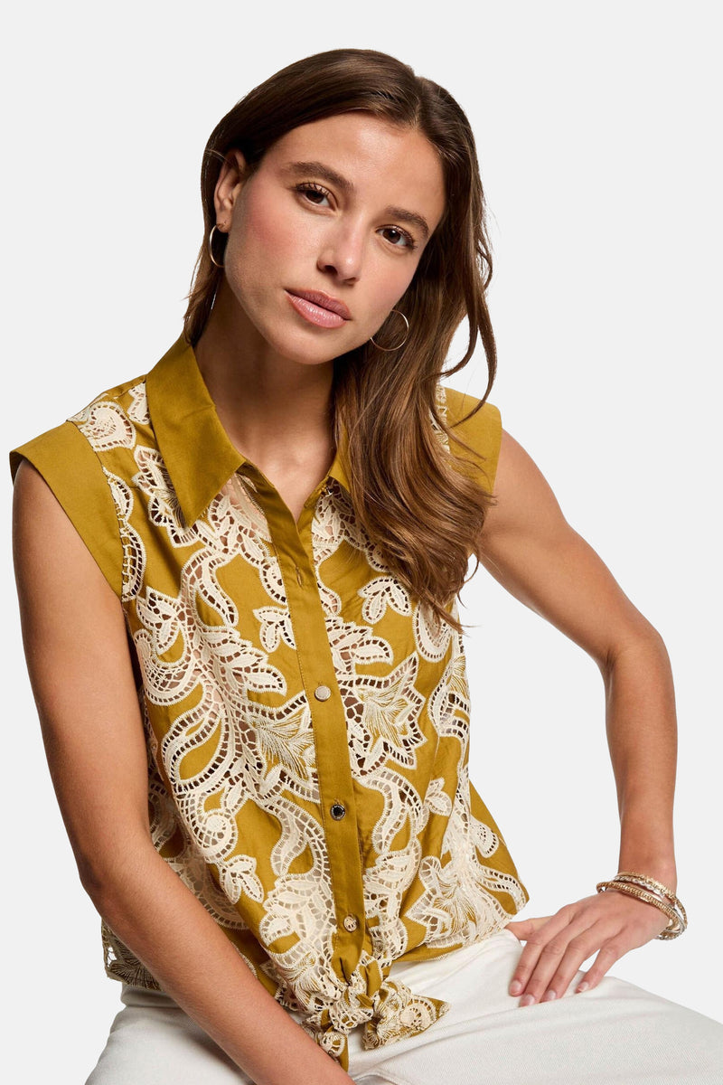 Chemisier jaune sans manches by Morgan de Toi, orné de dentelle blanche, porté avec des bijoux dorés.
