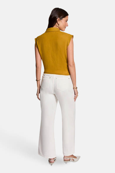 Chemisier jaune moutarde sans manches de Morgan de Toi, porté avec un pantalon blanc taille haute.