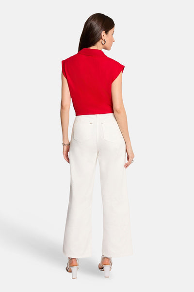 Rood mouwloos bloesje van Morgan de Toi, van achteren gedragen met een wijde witte jeans, zilverkleurige sieraden en hakken.