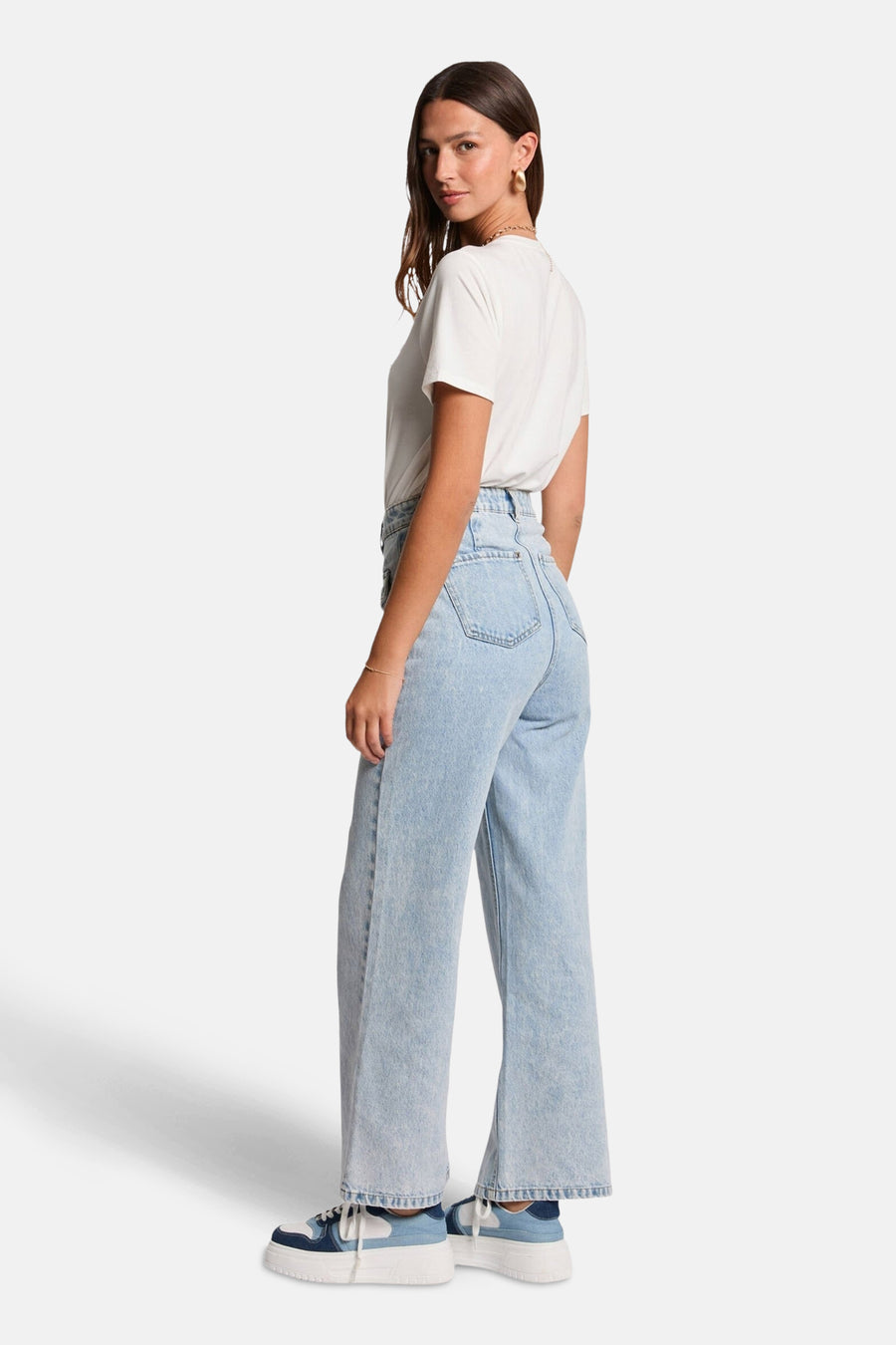 T-shirt blanc à manches courtes de Morgan de Toi, porté avec un jean taille haute ample et des baskets bleues et blanches.