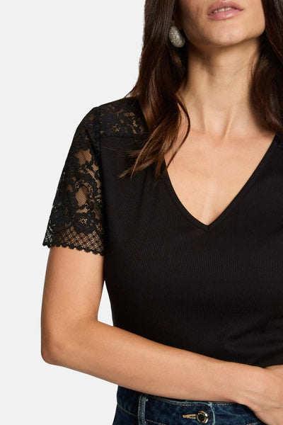 Black ribbed V-neck T-shirt with lace cap sleeves, cropped side view, model wearing jeans and statement earrings