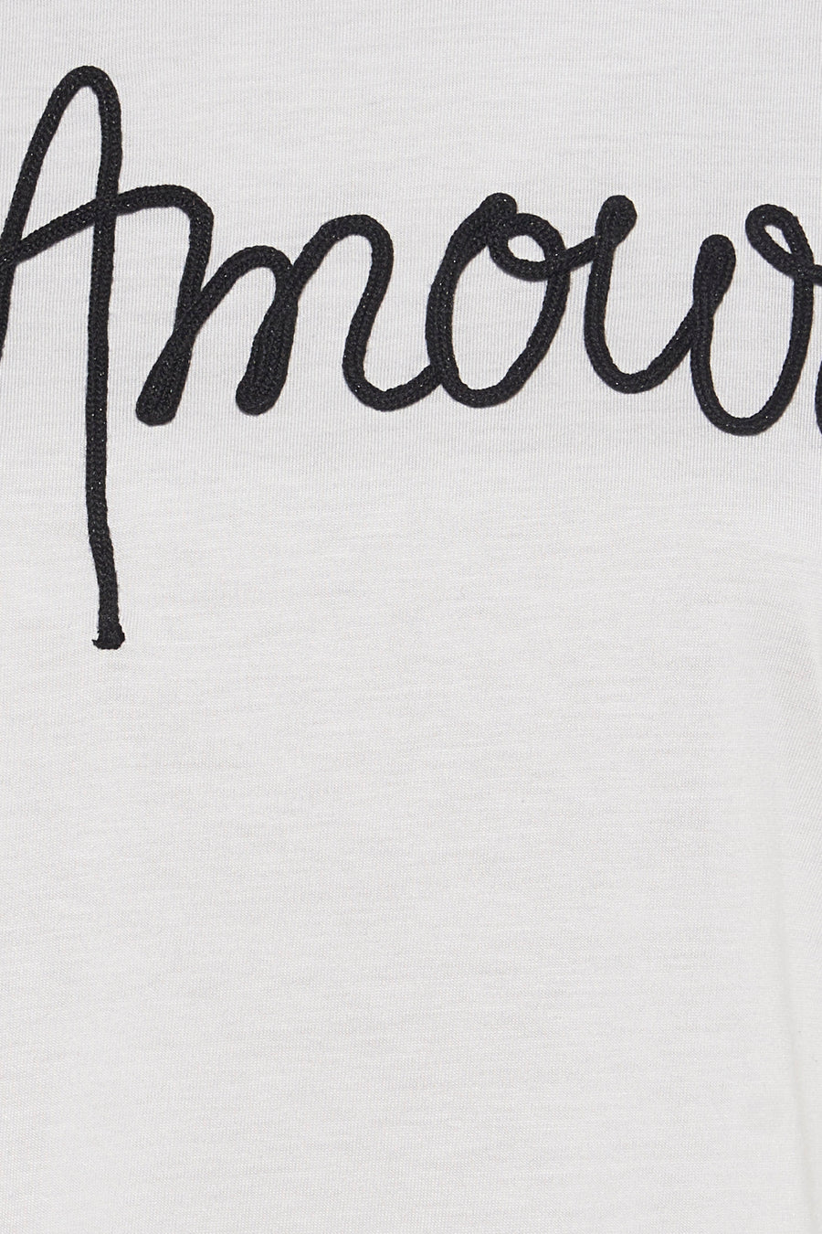 Top blanc en coton by Morgan de Toi avec broderie noire du mot « amour », en gros plan.
