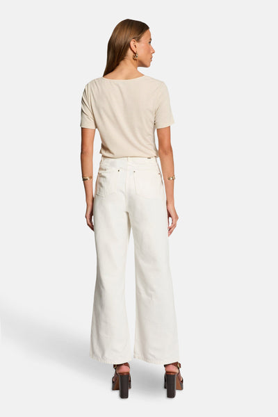 Beige T-shirt met korte mouwen van Morgan de Toi, horizontale strepen, gedragen met een wijde witte jeans en bruine hakken.