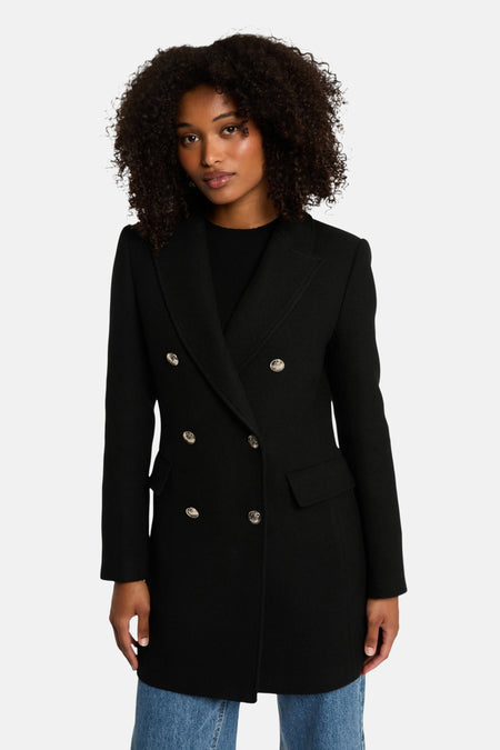 Veste noire croisée de Morgan de Toi avec boutons argentés, portée sur un pull noir et un jean.