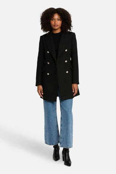 Veste noire de Morgan de Toi avec boutons dorés, portée avec un jean bleu et des bottines noires.