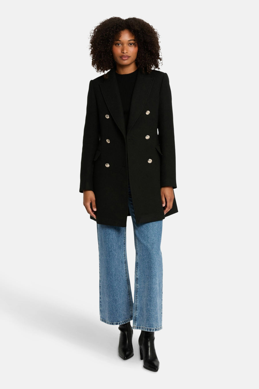 Veste noire de Morgan de Toi avec boutons dorés, portée avec un jean bleu et des bottines noires.