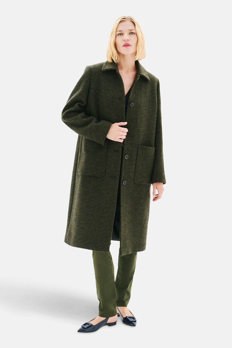 Lange groene geruite jas van Caroll, gedragen met een zwarte broek en schoenen, model op witte achtergrond.
