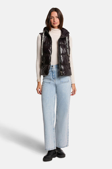 Veste sans manches noire de Morgan, avec capuche et fermeture éclair portée sur un pull à col roulé et un jean ample.
