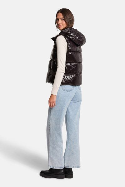 Veste sans manches noire de Morgan de Toi avec capuche, portée avec un pull blanc et un jean bleu.