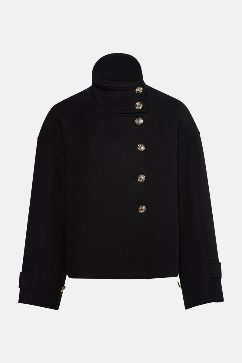 Korte zwarte jas van Morgan de Toi, met opstaande kraag en asymmetrische knoopsluiting.