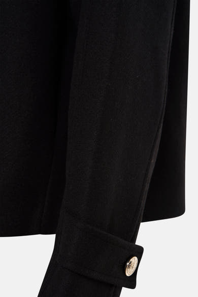 Veste courte noire de Morgan de Toi, avec un bouton doré sur le bas de la manche.