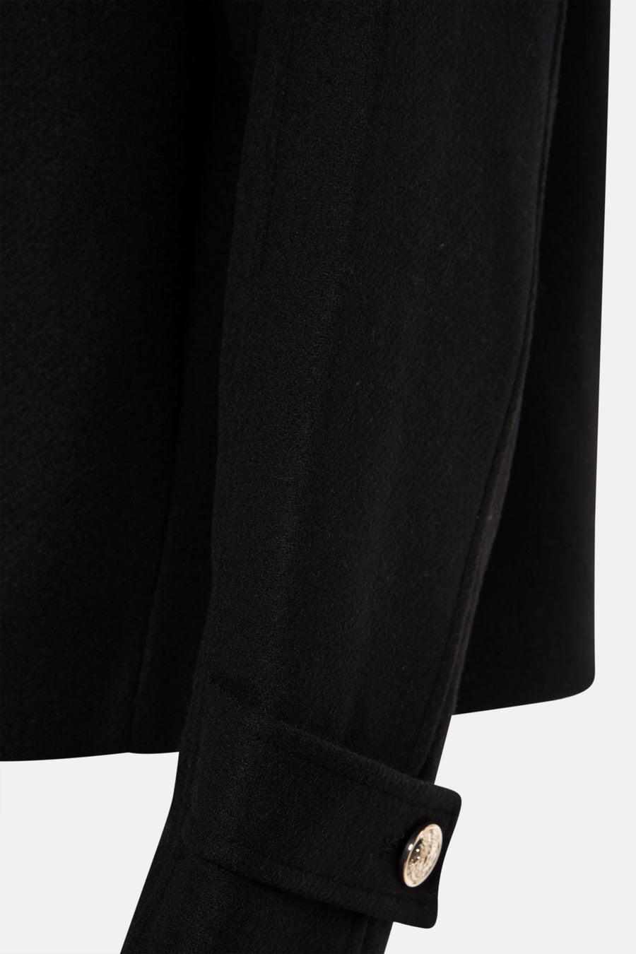 Veste courte noire de Morgan de Toi, avec un bouton doré sur le bas de la manche.