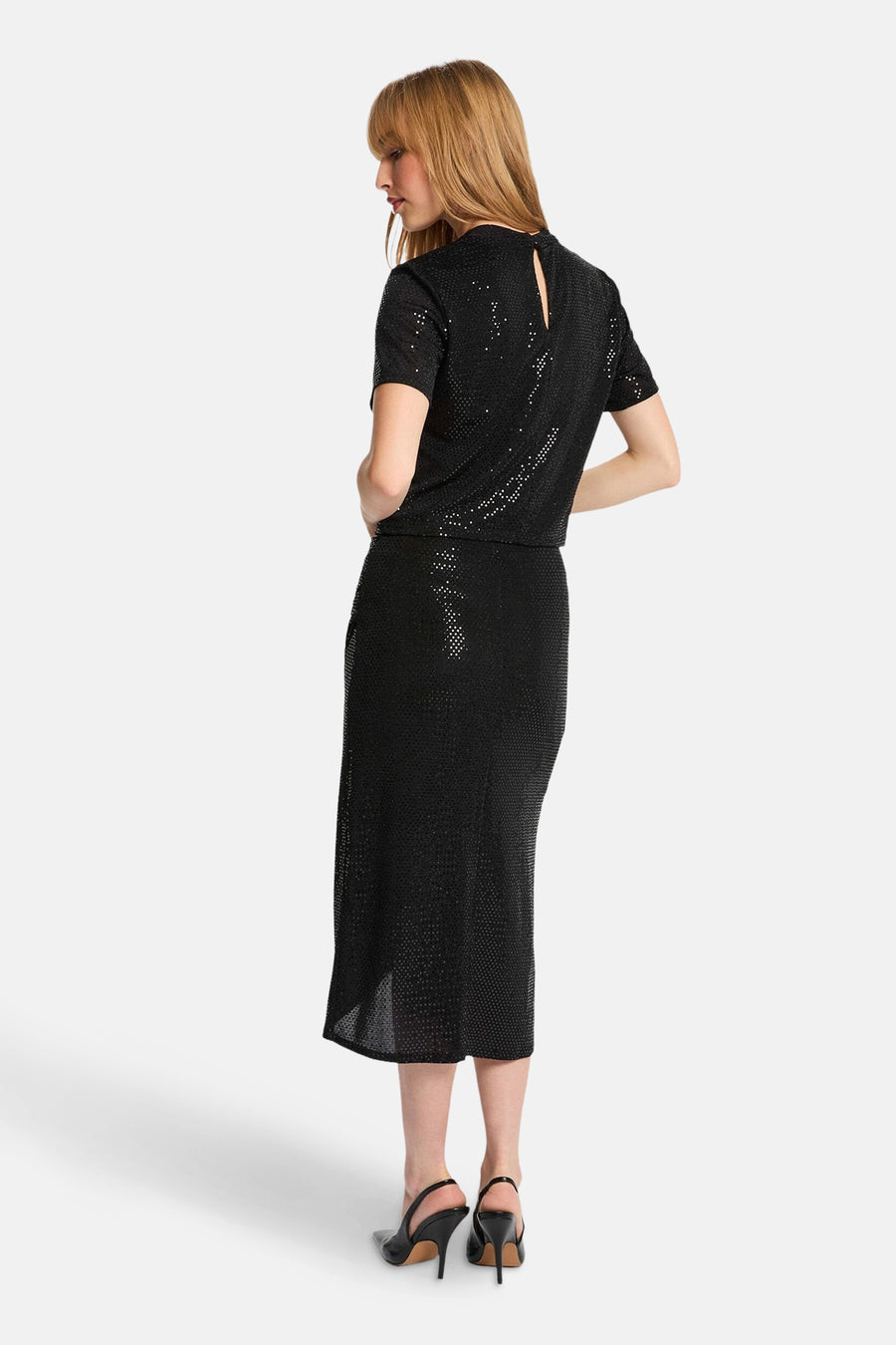 Jupe noire de Morgan de Toi, coupe midi droite avec motif texturé et ourlet fendu, portée avec des talons noirs.
