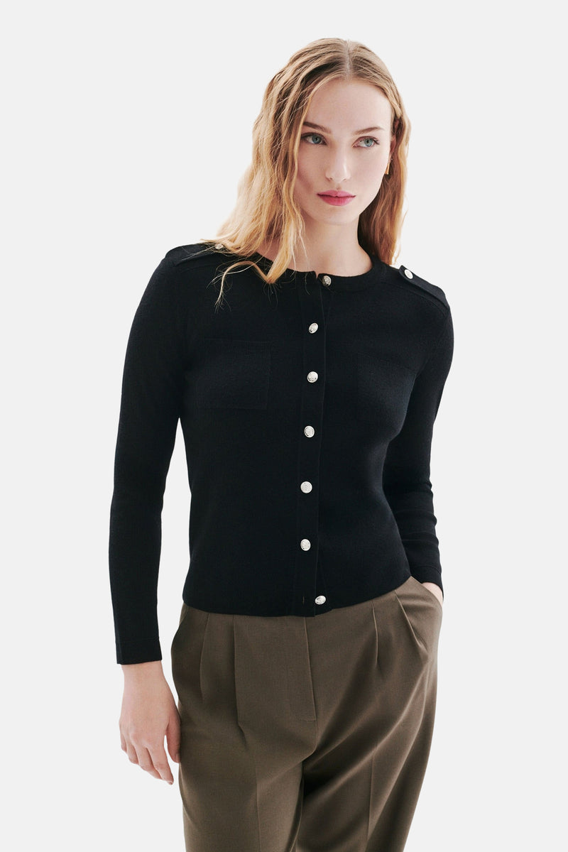 Zwarte CAROLL-cardigan met zilveren knopen, gedragen met golvend blond haar.