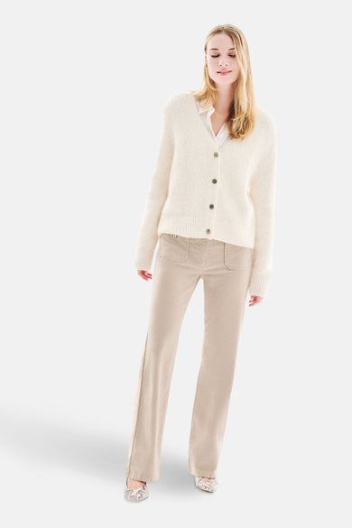 Witte, pluizige gebreide cardigan van CAROLL, gedragen over een wit overhemd met een beige broek.