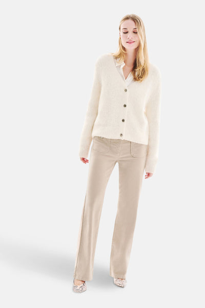 Witte, pluizige gebreide cardigan van CAROLL, gedragen over een wit overhemd met een beige broek.