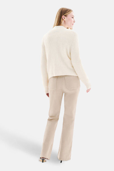 Cardigan blanc en maille duveteuse de CAROLL, avec un pantalon beige et des talons noirs.
