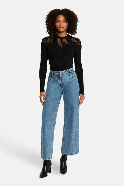 Zwarte trui met lange mouwen van Morgan de Toi, met een doorschijnend gestreept inzetstuk aan de bovenkant, gedragen met een high-waisted jeans.