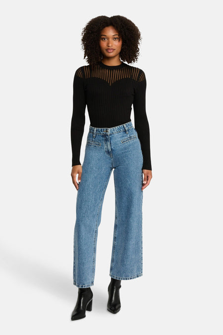 Pull noir à manches longues de Morgan de Toi, avec empiècement transparent rayé sur le haut, porté avec un jean taille haute.
