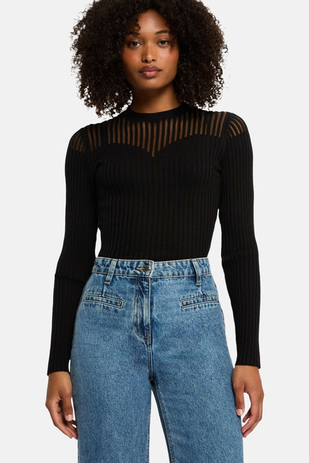 Pull noir by Morgan de Toi avec empiècement transparent à rayures verticales et jean bleu taille haute.
