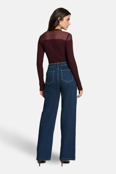 Bordeaux trui met lange mouwen van Morgan de Toi, met doorschijnend gestreept inzetstuk op de schouders, gedragen met een high-waisted jeans.