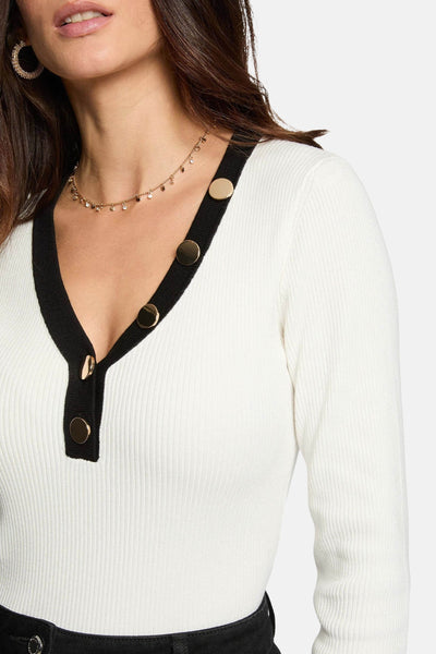 Pull à col en V blanc de Morgan de Toi avec boutons décoratifs dorés et un collier ras du cou.