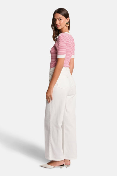 Roze gestreepte top van Morgan de Toi, gedragen met een witte high-waist jeans en muiltjes.