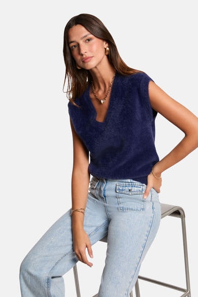 Blauwe, pluizige gebreide tanktop van Morgan de Toi, gedragen met een high-waisted jeans en gouden sieraden.