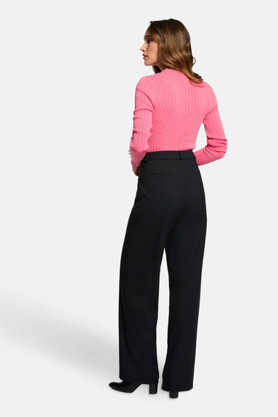 Pull rose à côtes, par Morgan de Toi, porté avec un pantalon rayé taille haute.
