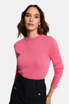 Roze ribgebreide top van Morgan de Toi, gedragen met een gestreepte broek en gouden oorbellen.