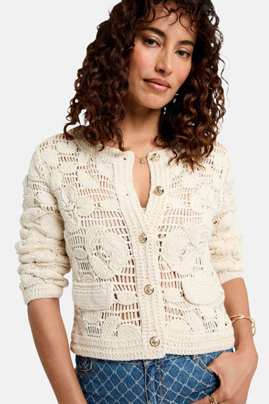 Gilet écru by Morgan de Toi avec des boutons dorés, motif floral ajouré et porté avec un jean.
