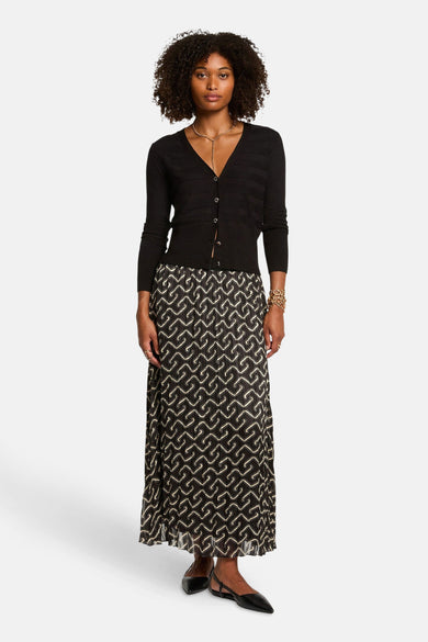 Zwarte gebreide cardigan van Morgan de Toi, gedragen met een lange rok met patroon en gouden sieraden.