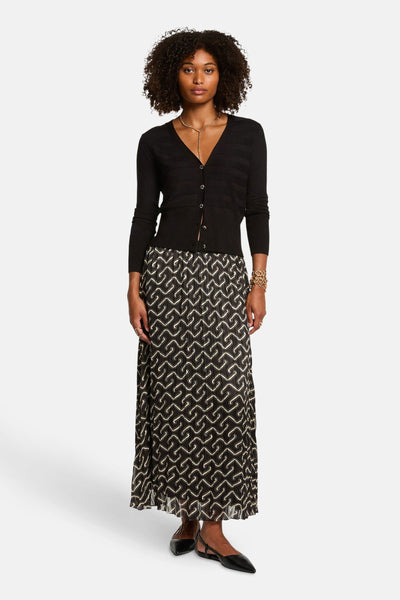Zwarte gebreide cardigan van Morgan de Toi, gedragen met een lange rok met patroon en gouden sieraden.