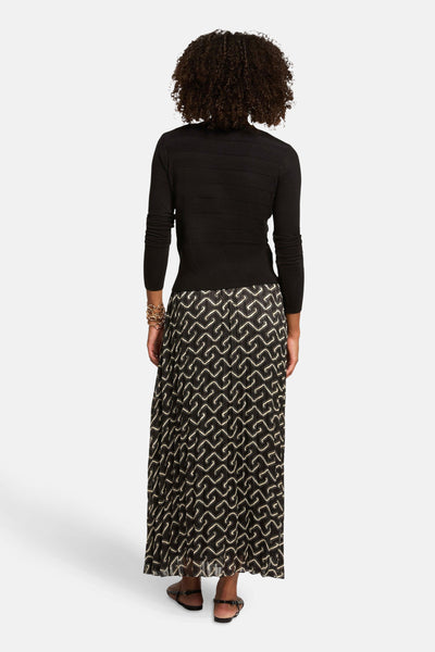Zwarte cardigan van Morgan de Toi, gedragen met een lange rok met patroon en een gouden armband.
