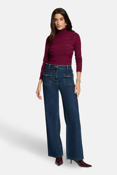 Bordeaux coltrui van Morgan de Toi, met horizontaal ribbelpatroon, gedragen met een high-waisted jeans en pumps.