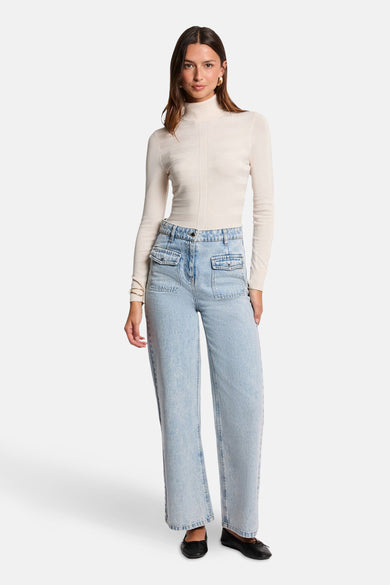 Ecru coltrui van Morgan de Toi, gedragen met een high-waisted jeans en zwarte platte schoenen.