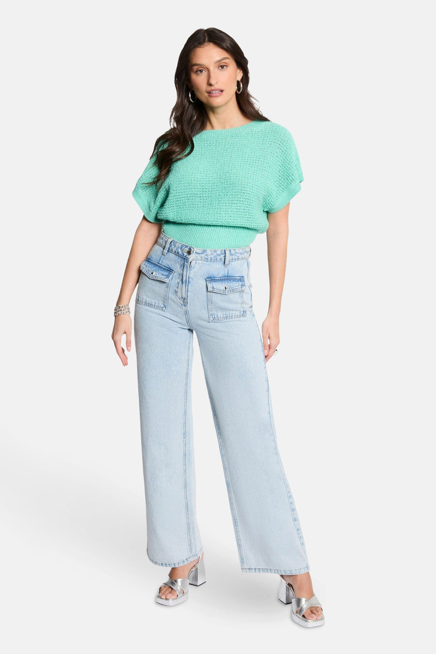 Groene trui met ronde hals van Morgan de Toi, gedragen met een high-waisted jeans en zilveren sandalen.
