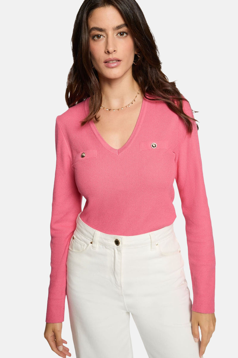 Roze trui met V-hals van Morgan de Toi, met twee zakken met gouden knopen en een witte broek.