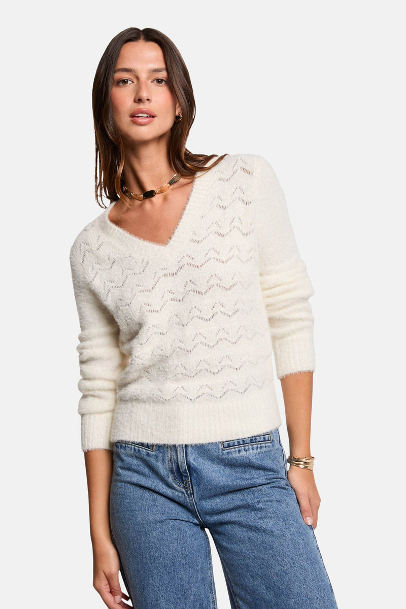 Witte V-hals trui van Morgan de Toi, met ajourpatroon, gedragen met een blauwe jeans.