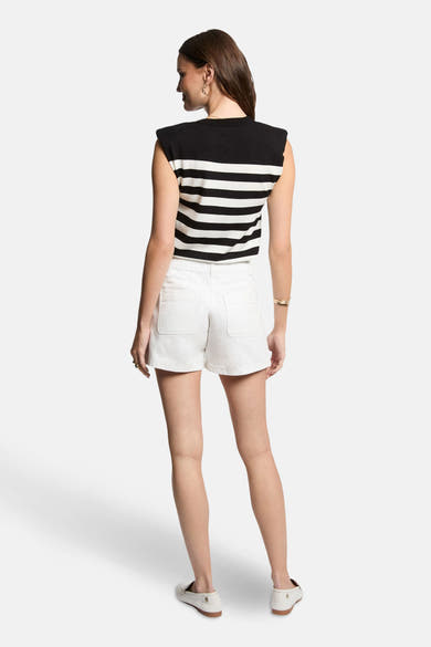 Top sans manches noir rayé by Morgan de Toi, porté avec un short blanc et des bijoux dorés.