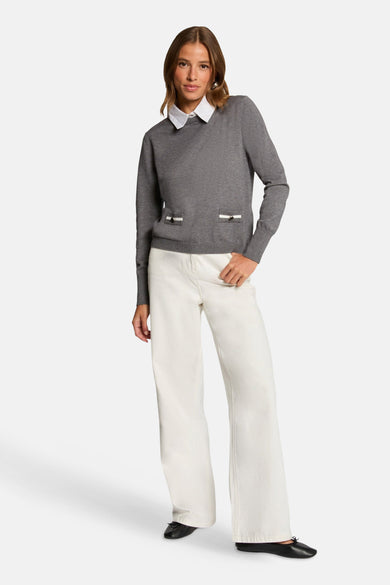Grijze Morgan de Toi trui, gedragen over een wit overhemd, met decoratieve zakken, gecombineerd met een witte broek met hoge taille.