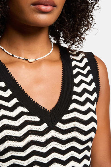 Top sans manches noir de Morgan de Toi avec motif ondulé, porté avec un collier de perles.
