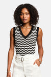 Top sans manches noir à motif chevron de Morgan de Toi, porté avec un pantalon taille haute blanc et un collier de coquillages.
