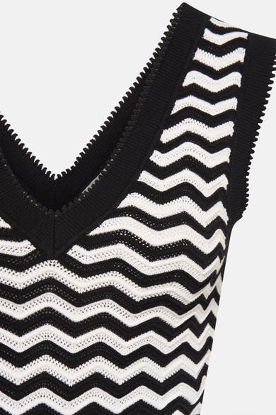 Top sans manches noir by Morgan de Toi, à motif ondulé blanc et finitions dentelées.
